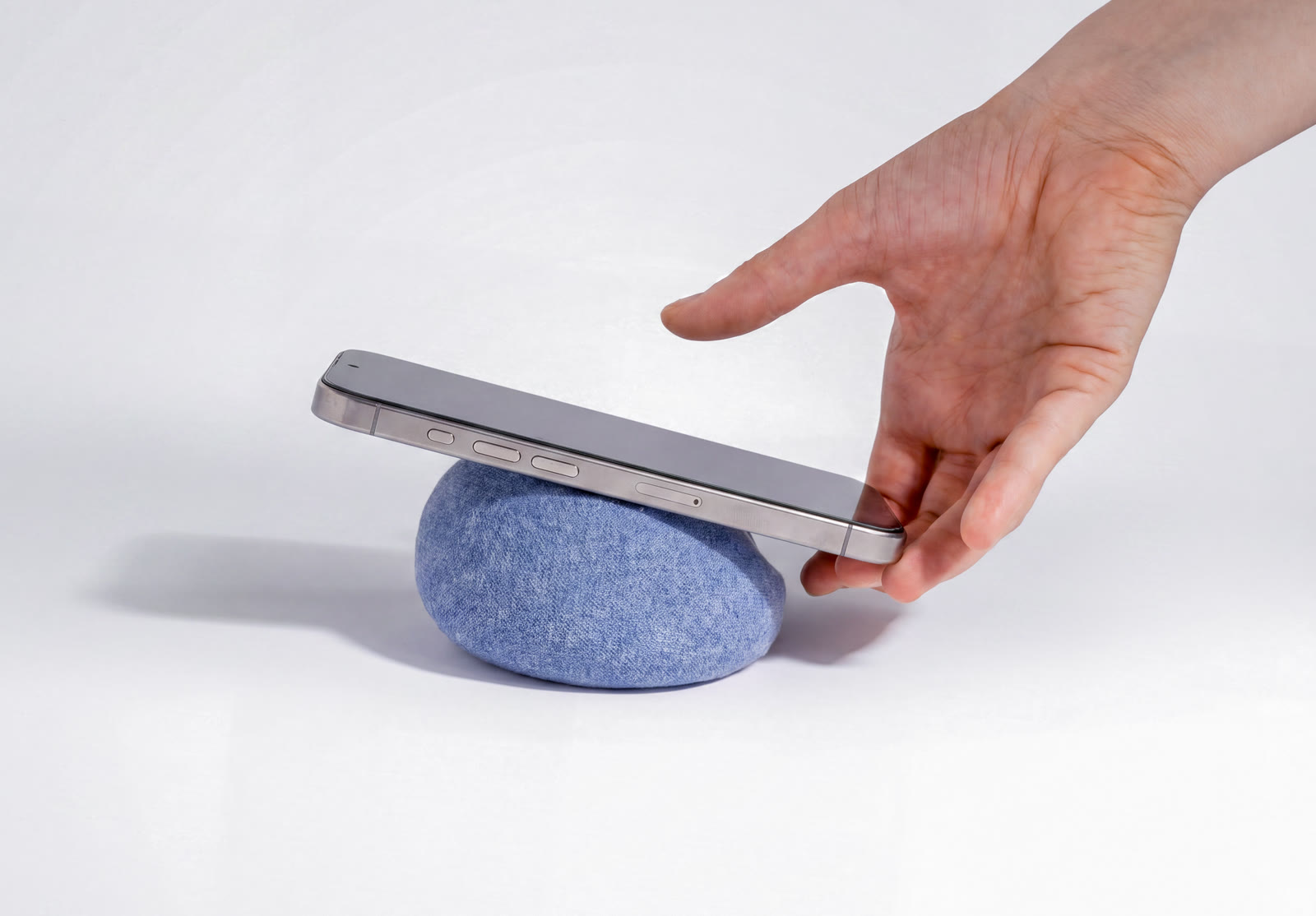 A fingertip settling the phone on NEST