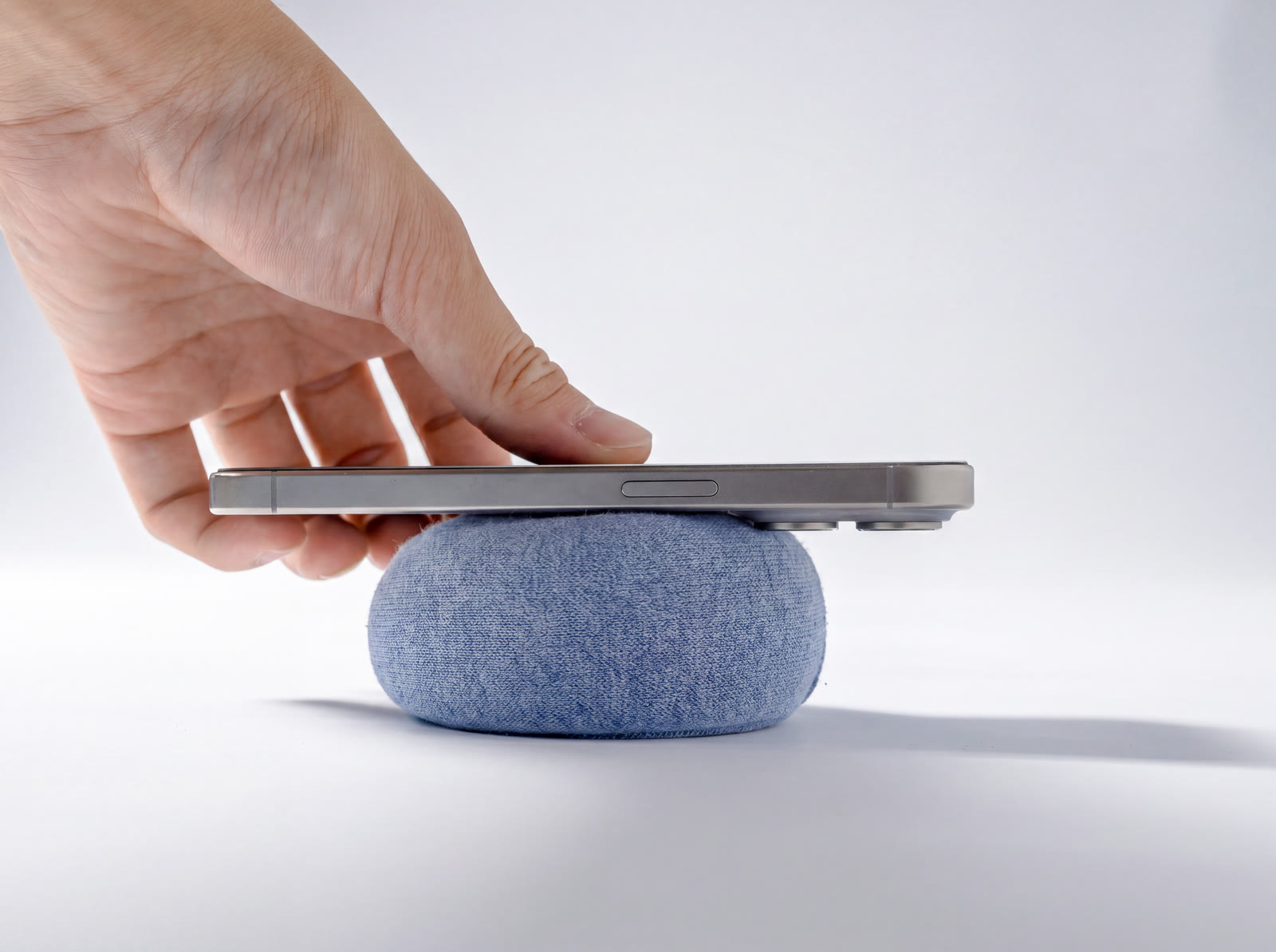 A hand lowering a phone onto NEST