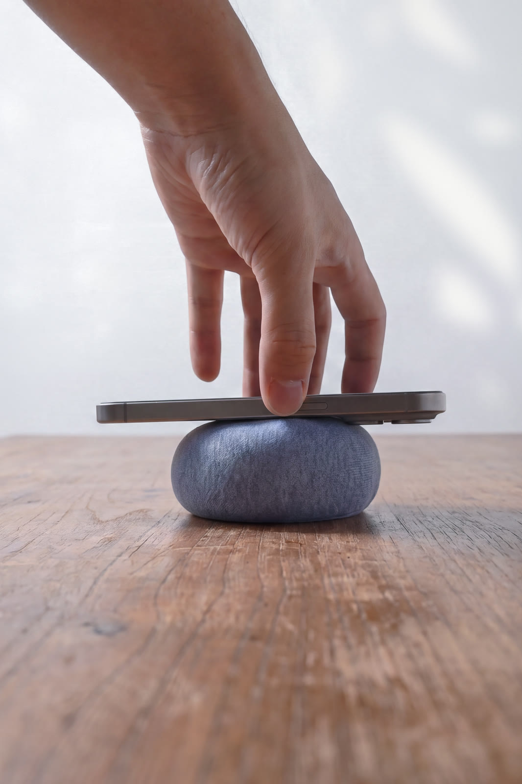 A hand pressing a phone down onto NEST